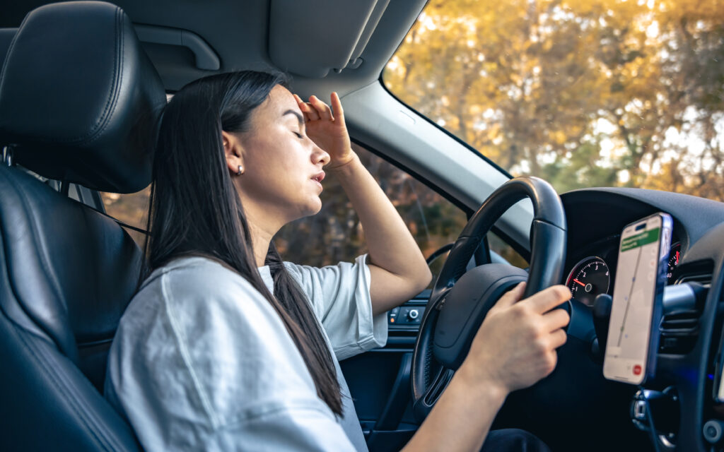 Tired young woman car driver suffering from headache migraine driving vehicle, unwell exhausted girl feeling sick and stressed inside automobile. 